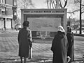 Een paar dames bestuderen aandachtig een plakkaat met de bouwtekening van de nieuw te bouwen brug. 1960.