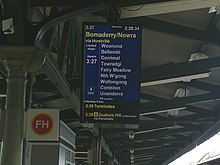 A Kiama service waiting to depart from Platform 7. Despite the destination of "Bomaderry/Nowra", the train terminates at Kiama and passengers must change for a diesel-powered train to Nowra. CityRail LCD Indicator Kiama Service.jpg