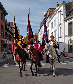 Les trois hérauts à cheval ouvrant la procession, portant les armoiries de la Belgique, de la ville de Tournai et du diocèse.