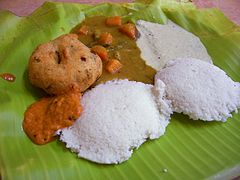 Idli và medu vada ăn kèm với sambar, chutney dừa và chutney đỏ trên lá chuối