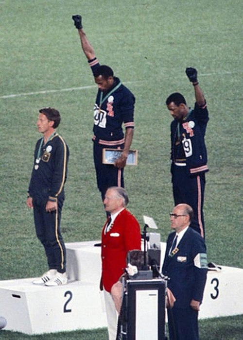 Gold medalist Tommie Smith (center) and bronze medalist John Carlos (right) showing the raised fist on the podium after the 200 m race