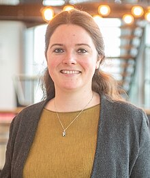 A smiling Caucasian woman with dark hair indoors