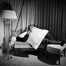 Джордж Лукас лежит на диване в гостиной Hotelzimmer mit einem Kissen auf dem Schoß.