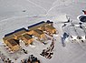 Vue aérienne de la station Amundsen-Scott. Le pôle Sud géographique est visible vers le haut et à gauche du centre de l'image, au-dessus des bâtiments et en dessous des traces de chenilles. Le pôle Sud de cérémonie, avec ses drapeaux, est visible à sa droite.