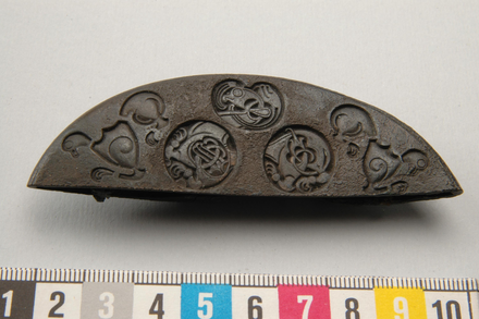 Fragment of a sword pommel decorated in Broa style, from grave 174 at Stora och Lilla Ihre, Hellvi parish, Gotland. Bronze. 550 – 800, Vendel age.