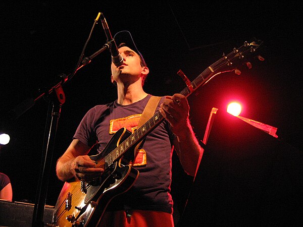 Sufjan Stevens performing on stage during a tour for Illinois. Stevens and his band the Illinoisemakers wore outfits modeled after those of the cheerl