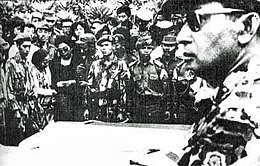 As Major General, Suharto (at right, foreground) attends the funeral for the generals assassinated in the abortive coup that led to the mass purge, 5 October 1965 Suharto at funeral.jpg