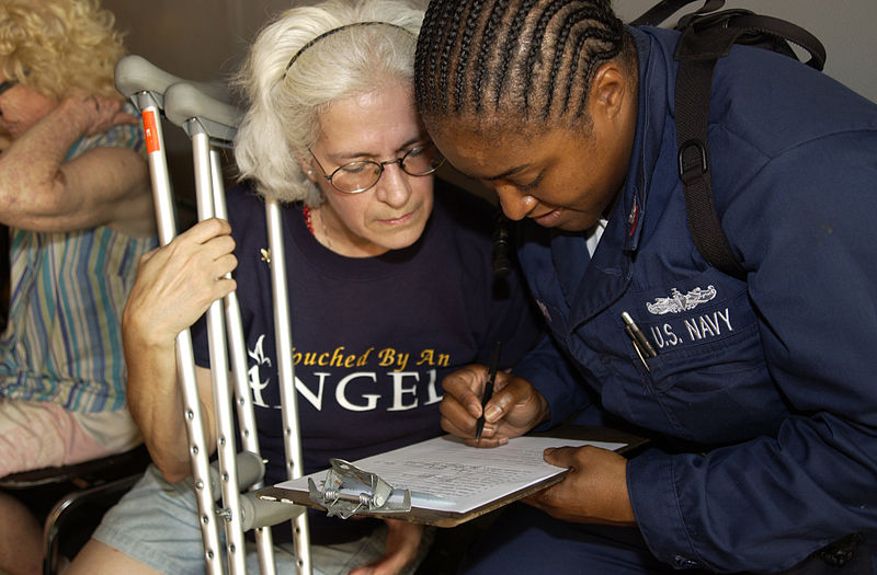 File:US Navy 050905-N-6436W-190 A U.S. Navy Sailor helps a Hurricane Katrina victim fill out paperwork after she was transported the dock landing ship USS Tortuga (LSD 46).jpg