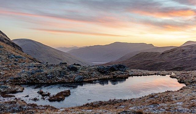 Un petit lac qui pourrait presque être une flaque d'eau. Une gelée blanche tapisse la lande ocre. Des collines laissent ouverte la perspective vers de petites montagnes. Le ciel bleu hésite entre le jour et la nuit.