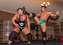 Page (right) hitting a big boot kick against Michael Elgin during a 2013 independent show Ethan Page bigboot Michael Elgin.jpg