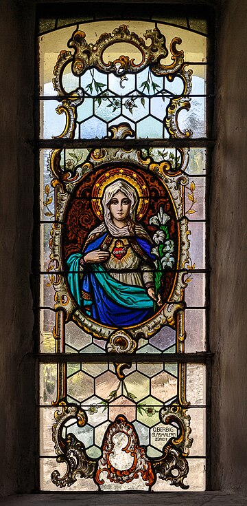 Este vitral de Oskar Berbig (1884–1930) retrata o Imaculado Coração de Maria. Está localizado na capela católica de Santo Antônio de Pádua, Andiast, Suíça. Hoje é o dia da festa do Imaculado Coração de Maria na Igreja Católica. É uma devoção católica romana que se refere à visão da vida interior de Maria, suas alegrias e tristezas, suas virtudes e perfeições ocultas e, acima de tudo, seu amor virginal por Deus, o Pai, seu amor maternal por seu filho Jesus Cristo e seu amor maternal e compassivo por toda a humanidade. Tradicionalmente, o Imaculado Coração é representado perfurado com sete espadas ou feridas, em homenagem às sete dores de Maria e rosas, geralmente vermelhas ou brancas, envoltas no coração. (definição 2 349 × 2 349)