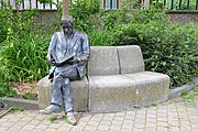 Sculpture en bronze d'un homme assis lisant un livre.