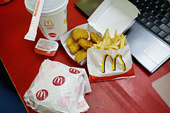Paper-wrapped food carrying McDonald's food; including Chicken McNuggets, fries, burger, and drink