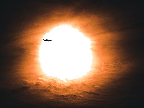 Plane flies in front of the sun