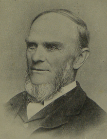 A historical photograph of a man with a receding hairline and a full beard, wearing a suit.