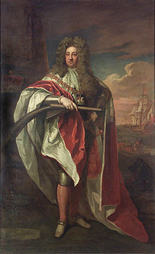 Prince George wearing a ducal robe with the collar of the Garter, by Godfrey Kneller, c. 1704. Behind him, a ship offshore is flying the Admiralty flag. Prince George as Lord High Admiral.jpg