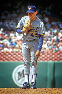 Un uomo in uniforme da baseball blu polvere con "Milwaukee" scritto sul petto e un berretto blu in piedi sul tumulo che si prepara a lanciare la palla