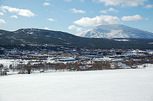 Foto einer Siedlung in einer verschneiten Region. Im Hintergrund befindet sich ein von Schnee bedeckter Berg.
