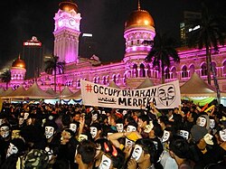 Protestors wear Guy Fawkes mask during the flash mob V for Merdeka flash mob protest on New Year's Eve.jpg