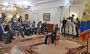 Russian President Vladimir Putin (seated, middle) speaks to the press on 4 March 2014, denouncing the Revolution of Dignity as an "unconstitutional coup", and insisting that Moscow has a right to protect Russians in Ukraine. Vladimir Putin answered journalists' questions on the situation in Ukraine (2014-03-04).jpeg