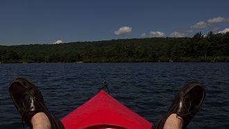 A boater in a kayak, facing north-west on Lake Tiorati. The largest island on Lake Tiorati is in the background on the right A view from a kayak, Lake Tiorati, NY, 2012.jpg