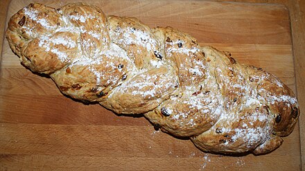 An unglazed Christmas Strietzel with raisins and flaked almonds, sprinkled with icing sugar