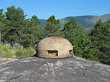 Фотография торчащей из бетона куполообразной брони, пробитой несколькими зубцами.