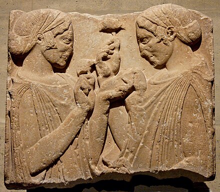 So-called "Exaltation de la Fleur" (exaltation of the flower), fragment from a grave stele: two women wearing a peplos and kekryphalos (hairnet), hold poppy or pomegranate flowers, and maybe a small bag of seeds. Parian marble, c. 470–460 BC. From Pharsalos, Thessaly.