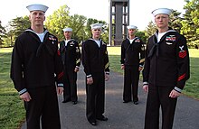 Petty officers in 2006 wearing service dress blue uniforms displaying both red and gold rating badges and service stripes. Five US Navy petty officers in uniform.jpg