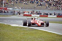 Красный гоночный автомобиль Ferrari выходит из поворота во время гонки