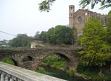 Vista di un ponte e di una chiesa romanici.