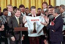 Jimmy Johnson and the 1987 Miami Hurricanes football team present President Ronald Reagan with a University of Miami jersey at The White House in January 1988 after winning the 1987 national championship Reagan with Miami Hurricanes football team 1988.jpg