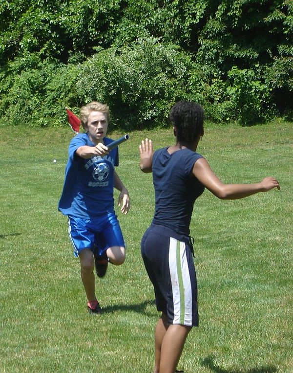 Two runners prepare to pass the baton.