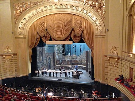 War Memorial Opera House in San Francisco, with a large golden proscenium arch, from which the stage curtains hang.  The drop from the stage to the orchestra pit, the proscaenium to the Romans, is in contrast painted black and given no emphasis at all.