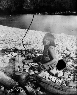 Kvinna i basttygsskjorta vid Tambopatafloden 1904. Hon sitter vid Svenska expeditionens lägereld. Foto: Erland Nordenskiöld.