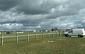 Photographie en couleurs d'un grand espace engazonné avec des agrès sportifs.