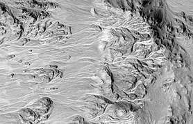 Cônes alluviaux dans le Cratère Mojave, vu par HiRISE. Réseau ramifié de canaux qui coulent d'un terrain plus élevé (cratère) au niveau le plus bas.