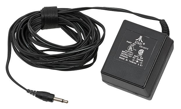 The Atari 2600 AC adapter takes AC electricity from mains and turns it 9 volt, 500 mAh DC current.