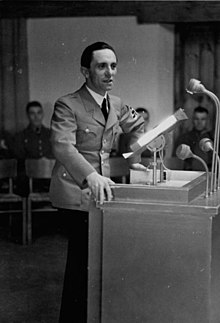Черно-белая фотография Йозефа Геббельса, стоящего за кафедрой в 1937 году.