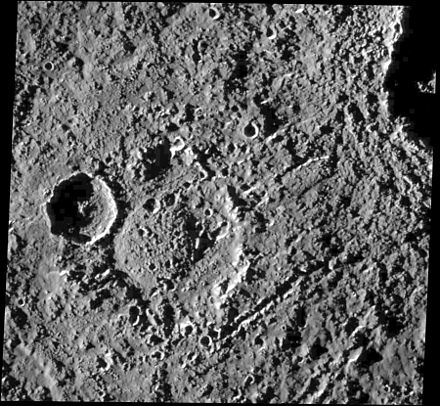 Impact crater Hár with a central dome. Chains of secondary craters from formation of the more recent crater Tindr at upper right crosscut the terrain.