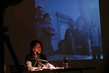 Author Stacey Levine reading at the Clear Cut Press presentation at MoMA's P.S.1 small press exhibition in February 2006. Projected photo shows Rich Jensen (left), Matthew Stadler (kneeling) Daniel Mitchell, Stacey Levine, Claire Evans, and Jona Bechtolt. ClearCutPress-StaceyLevine-PS1.jpg