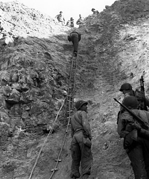 Amerikanske styrker klatrer op af den stejle klippekant.