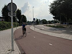 En dubbelriktad röd cykelbana i Amsterdam. En cyklist kommer cyklande mot fotografen.