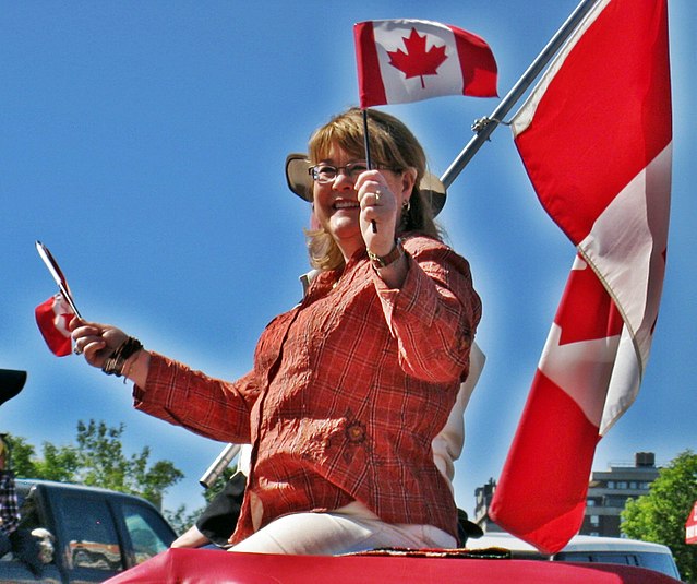 Diane Ablonczy waves the Canadian flag during the 2010 Calgary Stamepede parade.