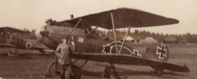 Photo noir et blanc d'un homme devant un avion biplan.
