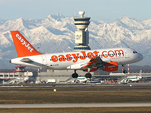 An easyJet Airbus A319-100 landing at Malpensa with the Alps visible in the background.