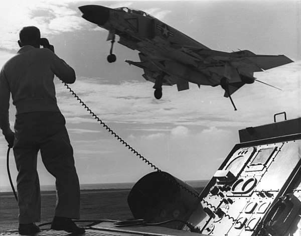 An F-4B from VF-21 as part of CVW-2 returns to the USS Midway after a combat mission over Vietnam in 1965. Pictured is CAG LSO, LCDR Vernon L. Jumper.