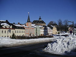 Pohled na místní náměstí s radnicí a zámkem v pozadí v zimě