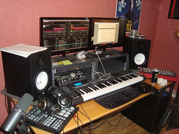 A typical home studio setup for EDM production with computer, audio interface and various MIDI instruments.