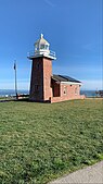 Red brick lighthouse on coastal cliff